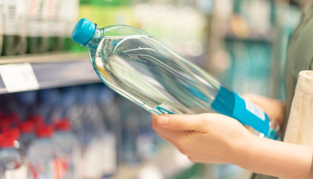persona che regge bottiglia d'acqua in plastica
